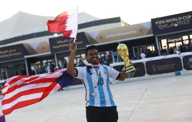 Fans membawa reflika trofi menhadiri pembukaan Piala Dunia 2022 Qatar dan pertandingan Qatar melawan Ekuador di Stadion Al Bayt, Al Khor, Qatar. Foto: Bernadett Szabo/REUTERS