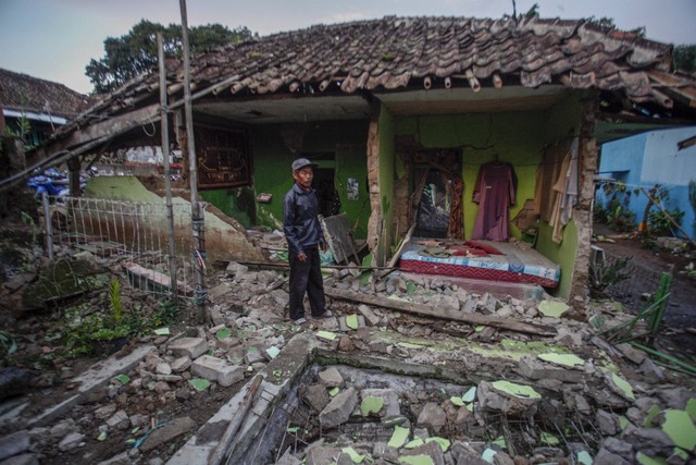 Warga berdiri di depan rumahnya yang rusak akibat gempa di Desa Cibeureum, Kabupaten Cianjur, Jawa Barat, Senin (21/11/2022).  Foto: Yulius Satria Wijaya/ANTARA FOTO