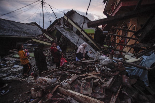 Warga melintas di depan rumah yang rusak akibat gempa di Desa Cibeureum, Kabupaten Cianjur, Jawa Barat, Senin (21/11/2022).  Foto: Yulius Satria Wijaya/ANTARA FOTO