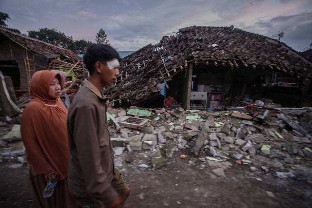 Warga melintas di depan rumahnya yang rusak akibat gempa di Desa Cibeureum, Kabupaten Cianjur, Jawa Barat, Senin (21/11/2022). Foto: Yulius Satria Wijaya/ANTARA FOTO