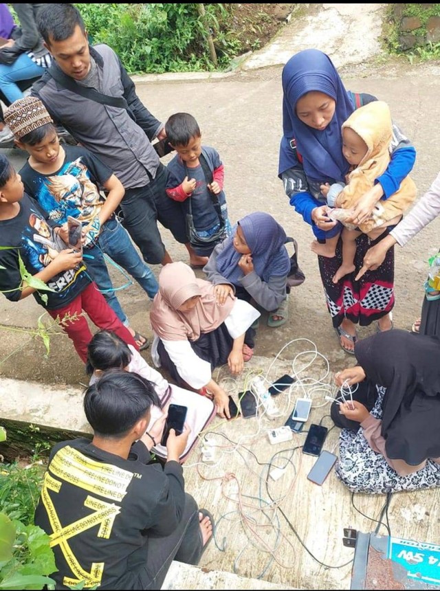 Warga sedang mengisi baterai ponsel mereka dari genset yang disediakan tim teknisi XL Axiata di Desa Cijedil, Kecamatan Cugenang, Cianjur, Selasa, 22 November 2022. Foto: Dok. XL Axiata