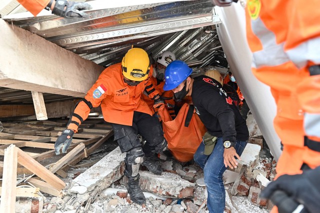 Petugas penyelamat membawa jenazah korban gempa di Cianjur, Jawa Barat, Selasa (22/11/2022). Foto: Adek Berry/AFP