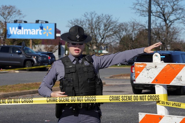 Polisi Negara Bagian Virginia memberi isyarat kepada anggota media untuk tetap berada di belakang tempat parkir setelah penembakan massal di Walmart di Chesapeake, Virginia, AS, Rabu (23/11/2022). Foto: Jay Paul/REUTERS