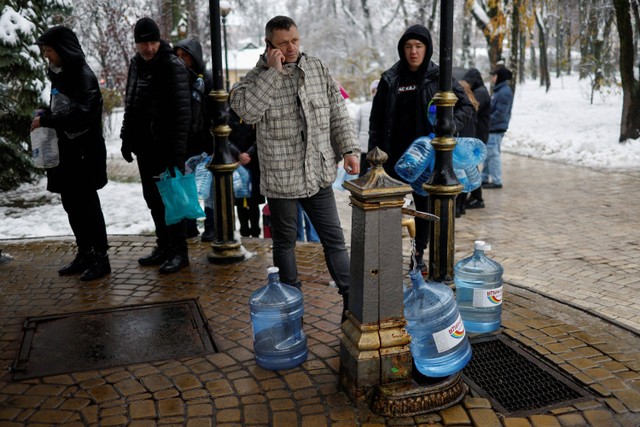 Warga antre untuk mengisi botol dengan air minum usai infrastruktur sipil kritis terkena serangan rudal Rusia di Kiev, Ukraina. Foto: Valentyn Ogirenko/REUTERS