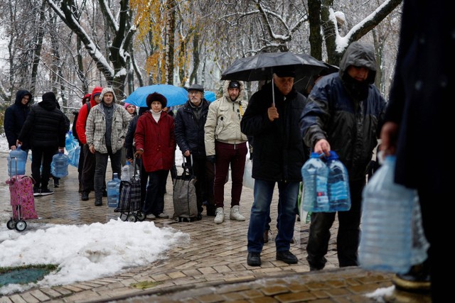 Warga antre untuk mengisi botol dengan air minum usai infrastruktur sipil kritis terkena serangan rudal Rusia di Kiev, Ukraina. Foto: Valentyn Ogirenko/REUTERS