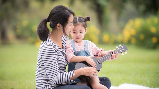 Seorang wanita mengajari putrinya bermain gitar. Foto: Nitikan T/Shutterstock.
