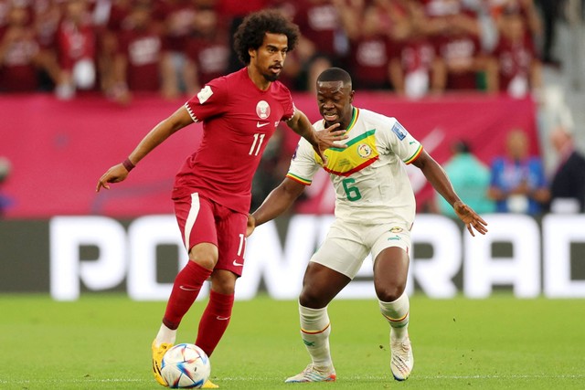 Pemain atar Akram Afif beraksi bersama pemain Senegal Nampalys Mendy pada Piala Dunia FIFA Qatar 2022 di Stadion Al Thumama, Doha, Qatar, Jumat (25/11/2022). Foto: Matthew Childs/REUTERS