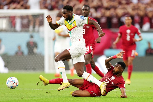 Pemain Qatar Ismail Mohamad beraksi bersama pemain Senegal Boulaye Dia pada Piala Dunia FIFA Qatar 2022 di Stadion Al Thumama, Doha, Qatar, Jumat (25/11/2022). Foto: Amr Abdallah Dalsh/REUTERS