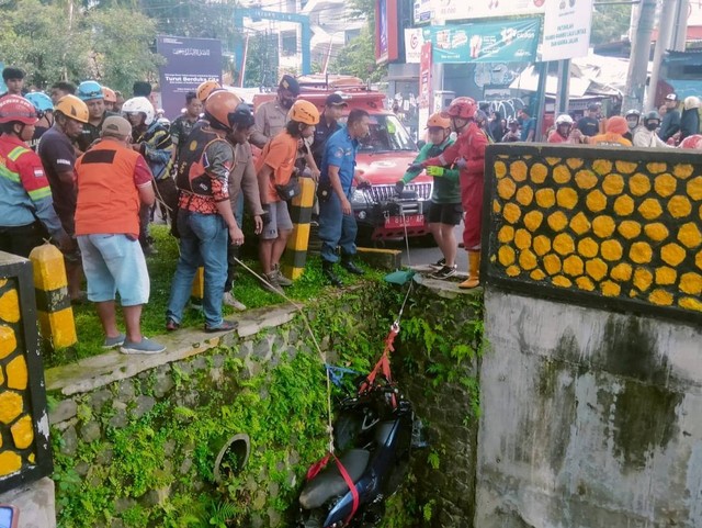 Para petugas mengevakuasi motor mahasiswa UMM yang jatuh di jembatan Suhat, Kota Malang. Foto/M Sholeh