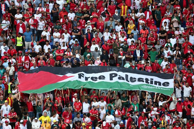 Fans membuka spanduk dengan pesan 'Bebaskan Palestina' pada laga Tunisia vs Australia di Piala Dunia 2022, di Stadion Al Janoub, Al Wakrah, Qatar, Sabtu (26/11/2022). Foto: Marko Djurica/REUTERS
