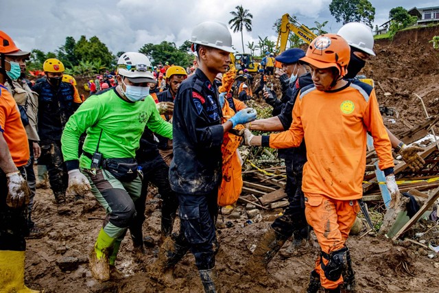 Petugas penyelamat membawa jenazah yang diambil dari puing-puing di desa Cugenang di Cianjur, Jawa Barat, Sabtu (26/11/2022). Foto: Mas Agung Wilis/AFP