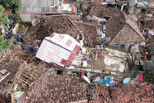 Tampilan udara menunjukkan petugas penyelamat bekerja untuk menyelamatkan seorang anak dari puing-puing rumah yang runtuh di Cugenang di Cianjur, Jawa Barat pada Kamis (24/11/2022). Foto: Adek Berry/AFP