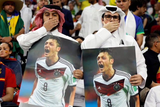Suporter membawa poster yang menampilkan mantan pemain Jerman Mesut Ozil saat pertandingan Spanyol melawan Jerman pada pertandingan Grup E Piala Dunia 2022 Qatar di Stadion Al Bayt, Al Khor, Qatar. Foto: John Sibley/REUTERS