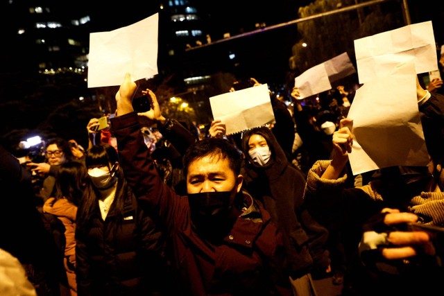 Sejumlah demonstran memegang kertas putih saat menggelar unjuk rasa pembatasan COVID-19 di Beijing, China. Foto: Thomas Peter/REUTERS