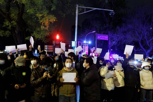 Sejumlah demonstran memegang kertas putih saat menggelar unjuk rasa pembatasan COVID-19 di Beijing, China. Foto: Thomas Peter/REUTERS