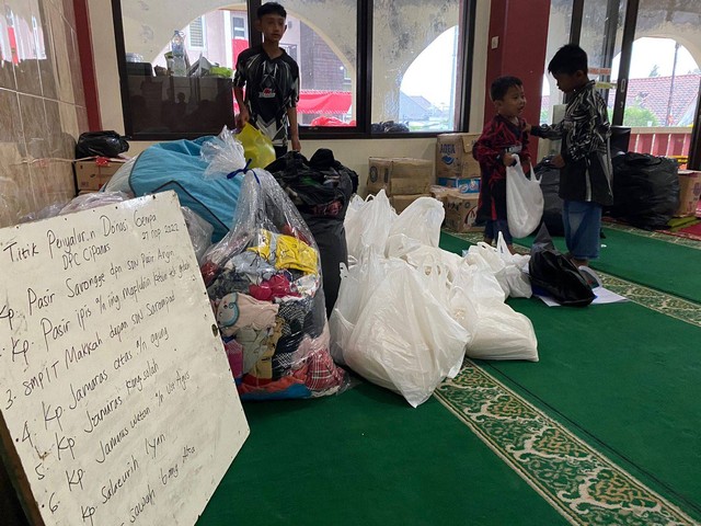 Warga yang mengungsi di masjid memindahkan kasur dan alas tidur dari teras masjid ke dalam karena teras bocor dan cipratan hujan dari luar, Senin (28/11/2022). Foto: Muhammad Iqbal/kumparan