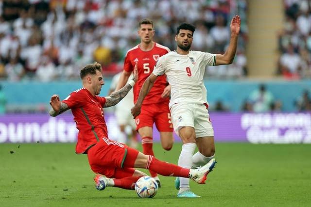 Pemain Wales Joe Rodon beraksi dengan pemain Iran Mehdi Taremi pada Piala Dunia FIFA Qatar 2022 di Stadion Ahmad Bin Ali, Al Rayyan, Qatar, Jumat (25/11/2022). Foto: Carl Recine/REUTERS