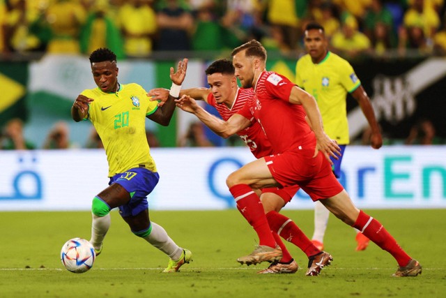 Pemain Timnas Brasil Vinicius Junior berusaha melewati pemain Timnas Swiss Fabian Rieder dan Silvan Widmer pada pertandingan Grup G Piala Duia 2022 Qatar di Stadion 974, Doha, Qatar. Foto: Pedro Nunes/REUTERS