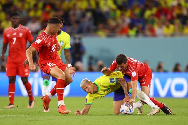 Pemain Timnas Brasil Richarlison berebut bola dengan pemain Timnas Swiss Remo Freuler pada pertandingan Grup G Piala Duia 2022 Qatar di Stadion 974, Doha, Qatar. Foto: Hannah McKay/REUTERS