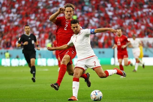 Pemain Timnas Denmark Joachim Andersen berebut bola dengan pemain Timnas Tunisia Youssef Msakni pada pertandingan Grup D Piala Dunia 2022 Qatar di Education City Stadium, Al Rayyan, Qatar. Foto: Kai Pfaffenbach/REUTERS