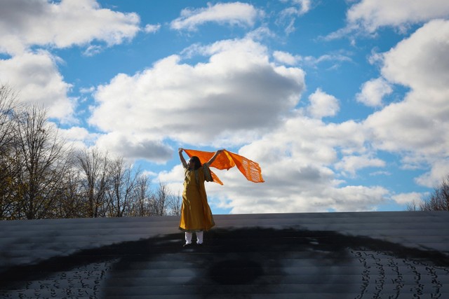 Seorang pria melambaikan syalnya yang tertiup angin saat dia berdiri di tangga saat pembukaan "Eyes on Iran," di Franklin D Roosevelt Four Freedoms State Park, Pulau Roosevelt, New York City, New York, AS, Senin (28/11/2022). Foto: Mike Segar/REUTERS