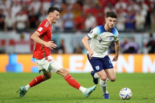 Pemain Timnas Inggris Declan Rice  berusaha melewati pemain Timnas Wales Kieffer Moore pada pertandingan Grup B Piala Dunia 2022 Qatar di Stadion Ahmad Bin Ali, Al Rayyan, Qatar. Foto: Carl Recine/REUTERS