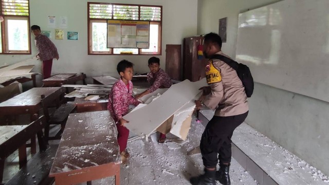 Polisi bersama beberapa orang siswa yang membersihkan plafon SD di Gunungkidul yang ambruk. Foto: Tugu Jogja