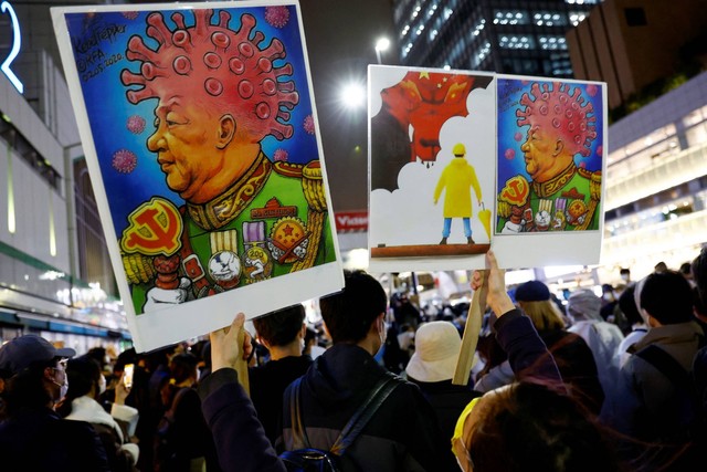 Warga China yang tinggal di Jepang memegang plakat yang menggambarkan Presiden China Xi Jinping, selama protes solidaritas menentang penguncian COVID-19 China, di Tokyo, Jepang, Rabu (30/11/2022). Foto: Kim Kyung-Hoon/REUTERS