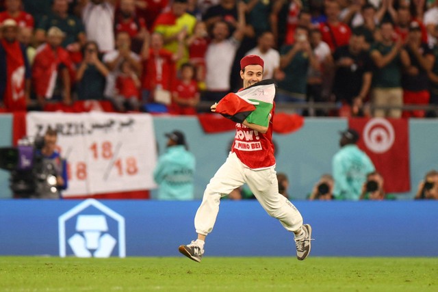 Seorang suporter memegang bendera Palestina masuk ke lapangan saat pertandingan Timnas Prancis melawan Timnas Tunisia pada pertandingan lanjutan Grup D Piala Dunia 2022 Qatar di Education City Stadium, Al Rayyan, Qatar. Foto: Hannah McKay/REUTERS