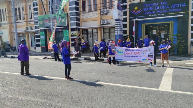 Dinkes Blora bersama aktivis dan penyintas AIDS, saat membagikan bunga dan brosur tentang HIV/AIDS, kepada pengendara yang melintas di jalan protokol di Kota Blora. Kamis (01/12/2022). (foto: Dok Istimewa)