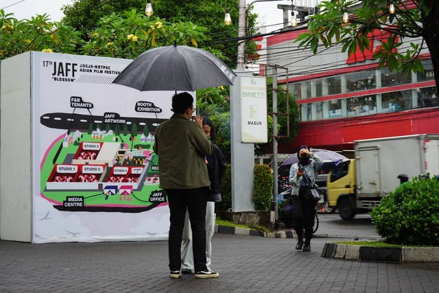Pengunjung JAFF 2022 sedang sedang memakai payung di tengah hujan. Foto: Arif UT
