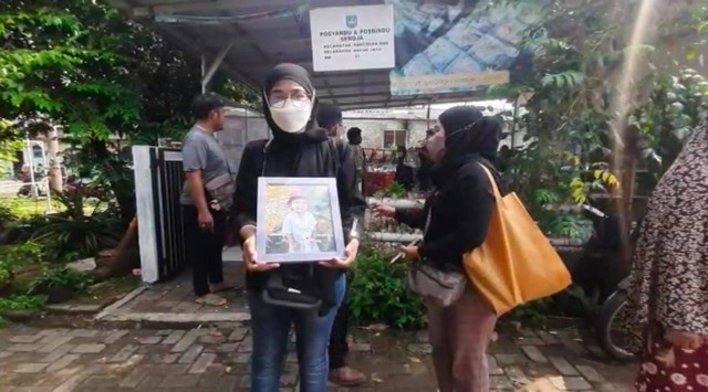 Seorang wanita membawa foto balita yang tewas diduga dianiaya kekasih ibu kandungnya. Foto: Dok. Istimewa