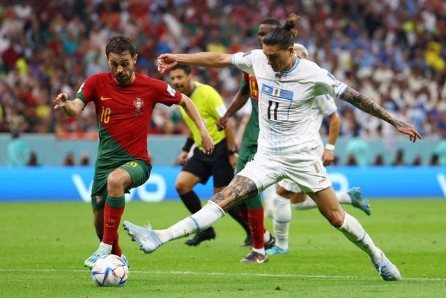 Pemain Timnas Portugal Bernardo Silva berebut bola dengan pemain Timnas Uruguay Darwin Nunez pada pertandingan Grup H Piala Dunia 2022 Qatar di Stadion Lusail, Lusail, Qatar. Foto: Kai Pfaffenbach/REUTERS