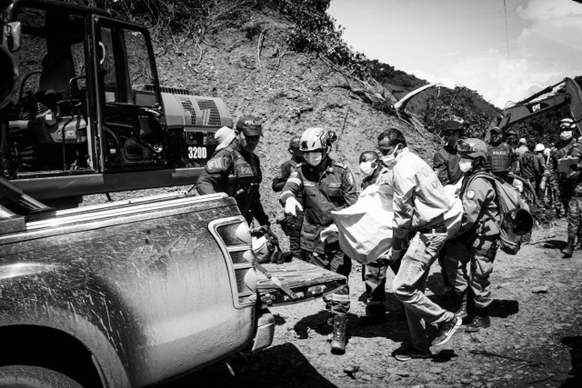 Petugas pemadam kebakaran dan anggota tim penyelamat membawa jenazah orang yang meninggal selama operasi penyelamatan setelah sebuah bus tertimbun tanah longsor akibat hujan lebat di Pueblo Rico, Kolombia, Senin (5/12/2022). Foto: Alexis Munera/REUTERS