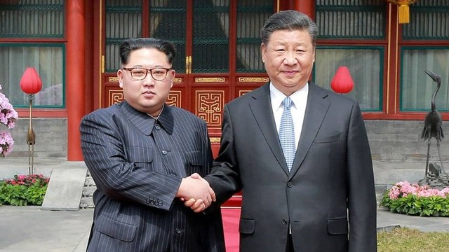 Presiden Korea Utara Kim Jong-Un (kiri) dan Presiden Tiongkok Xi Jinping (kanan) berjabat tangan (South China Morning Post)