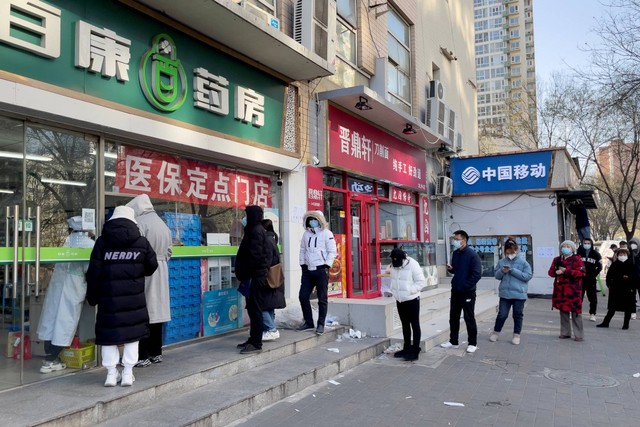 Orang-orang yang memakai masker mengantre di luar apotek untuk membeli obat di sebuah apotek di Beijing, China, Selasa (6/12/2022). Foto: Alessandro Diviggiano/REUTERS