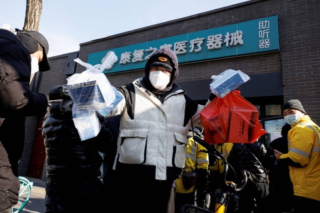 Petugas jasa pengiriman mengambil pesanan obat di sebuah apotek, di Beijing, China, Selasa (6/12/2022). Foto: Thomas Peter/REUTERS
