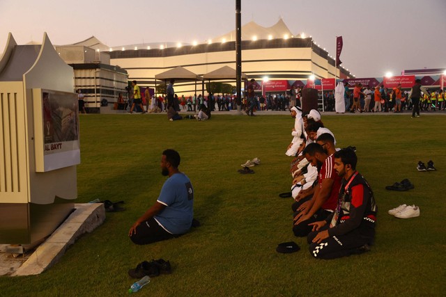 Fans sedang salat di luar stadion sebelum pertandingan Grup A Qatar vs Ekuador di Stadion Al Bayt, Al Khor, Qatar, Minggu (20/11/2022). Foto: Bernadett Szabo/Reuters