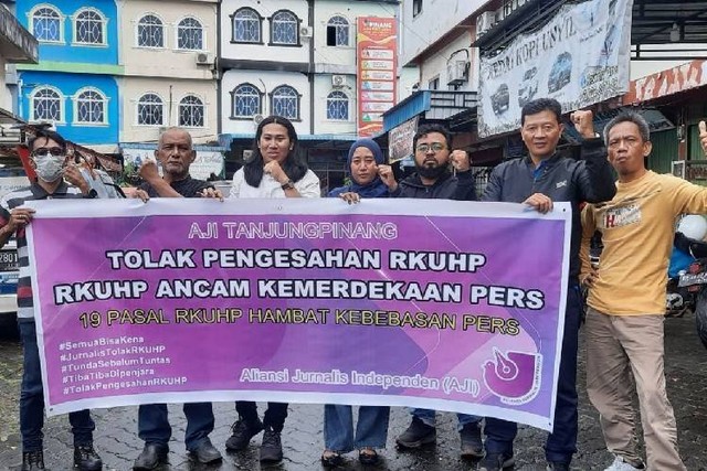 Ketua AJI Tanjungpinang, Jailani (baju putih) saat membentangkan spanduk tolak pengesahan RKUHP bersama sejumlah anggota AJI. (Foto: Istimewa)