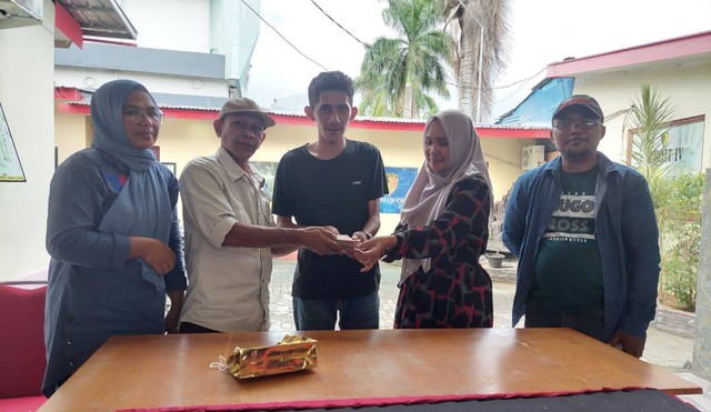 Ongen didampingi seorang keluarga saat menerima uang ganti rugi dari orang tua 3 tersangka anggota Polres Halmahera Utara. Foto: Istimewa