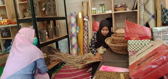 Ibu Kartini saat menjelaskan kepada seorang pengunjung yang berkunjung tentang produk hhbk dan produk panganan lokal di stan pameran. (Foto : Salmah/Yayasan Palung).