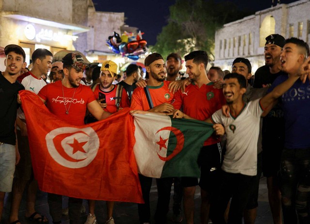 Penggemar dengan bendera Tunisia dan Aljazair bersorak di kawasan wisata populer di Souq Waqif, menjelang turnamen sepak bola Piala Dunia FIFA 2022 di Doha, Qatar 13 November 2022. Foto: REUTERS/Amr Abdallah Dalsh