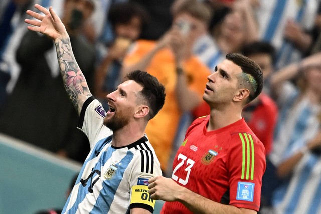 Pemain Argentina Lionel Messi dan Emiliano Martinez merayakan kemenangan setelah lolos ke babak berikutnya setelah mengalahkan Belanda dalam adu penalti. Foto: Manan Vatsyayana / AFP