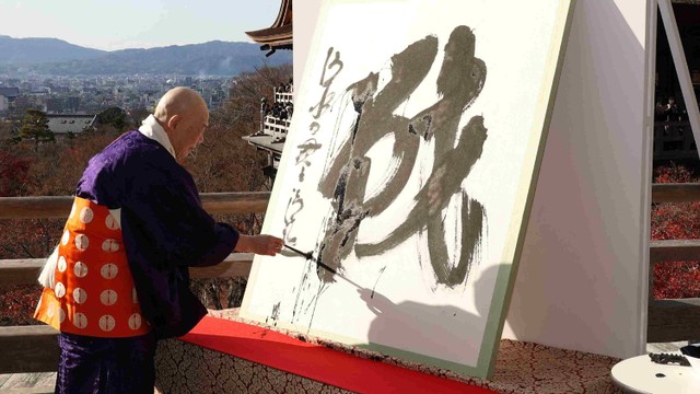 Seihan Mori, master kuil Kiyomizu kuno, menulis aksara Tionghoa, yang dikenal di Jepang sebagai "kanji", untuk 'perang', yang terpilih sebagai kanji tunggal terbaik untuk melambangkan tahun 2022 di sebuah kuil di Kyoto, Senin (12/12/2022). Foto: STR / JIJI PRESS / AFP