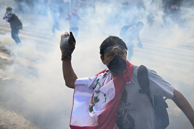 Pendukung mantan Presiden Peru Pedro Castillo melemparkan tabung gas air mata ke arah polisi anti huru hara selama protes di dekat Kongres di Lima, Peru, Senin (12/12/2022). Foto: Ernesto Benavides/AFP