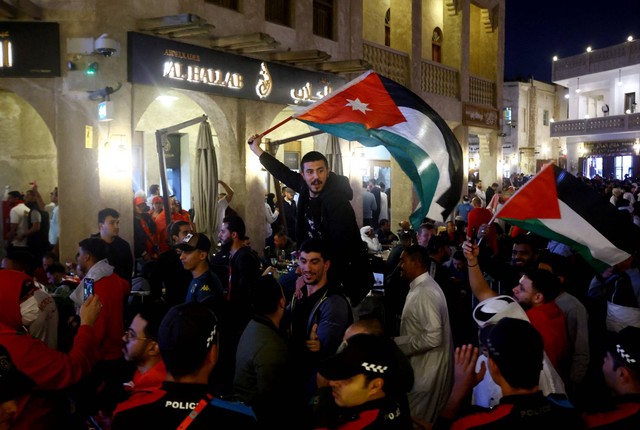Penggemar Maroko di Souq Waqif, mengibarkan bendera Yordania dan Palestina untuk merayakan saat Maroko maju ke semi final setelah pertandingan Maroko dan Portugal, di Doha, Qatar, 10 Desember 2022. Foto: Ibraheem Al Omari/REUTERS