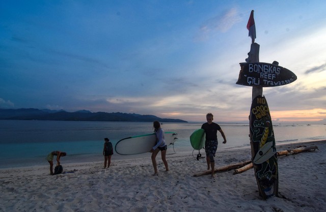 Wisatawan asing membawa papan surfing di pinggiran pantai wisata Gili Trawangan, Kecamatan Pemenang, Tanjung, Lombok Utara, NTB, Rabu (14/12/2022).  Foto: Ahmad Subaidi/ANTARA FOTO