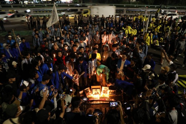 Massa mahasiswa menaburkan bunga di depan foto korban yang meninggal saat demo RKUHP pada tahun 2019 di sejumlah daerah saat unjuk rasa menolak RKUHP di DPR, Jakarta, Kamis (15/12/2022). Foto: Aditia Noviansyah/kumparan