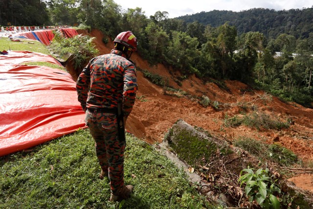 Tim penyelamat bekerja selama operasi pencarian korban longsor di perkemahan di Batang Kali, Selangor, Malaysia, Minggu (17/12).  Foto: Hasnoor Hussain/REUTERS