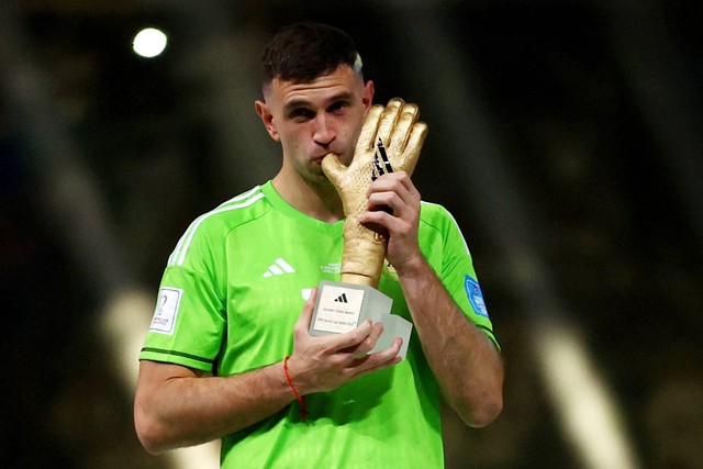 Pemain Argentina Emiliano Martinez mencium piala penghargaan Golden Glove di Stadion Lusail, Lusail, Qatar, Minggu (18/12/2022). Foto: Carl Recine/REUTERS